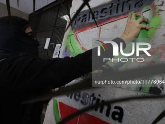 A pro-Palestine activist in Mexico City, Mexico, paints graffiti outside the Ministry of Foreign Affairs, where more people demand that Clau...