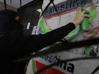 A pro-Palestine activist in Mexico City, Mexico, paints graffiti outside the Ministry of Foreign Affairs, where more people demand that Clau...