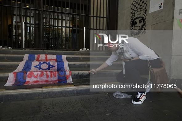 A pro-Palestine activist in Mexico City, Mexico, burns an Israeli flag outside the Ministry of Foreign Affairs, where more people demand tha...