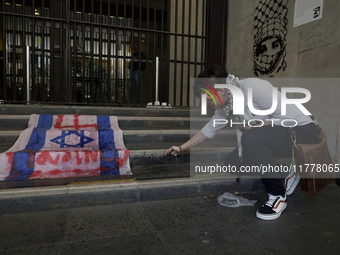 A pro-Palestine activist in Mexico City, Mexico, burns an Israeli flag outside the Ministry of Foreign Affairs, where more people demand tha...