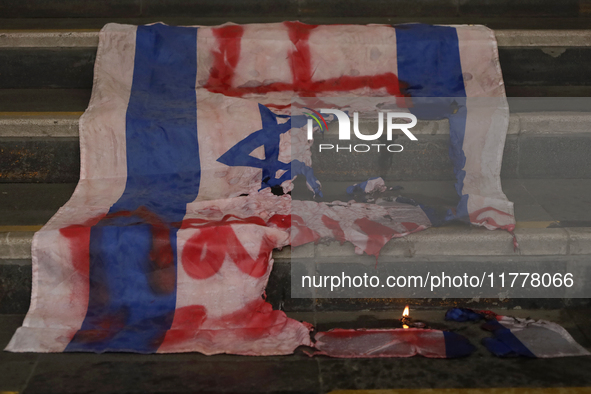 A pro-Palestine activist burns an Israeli flag in Mexico City, Mexico, outside the Ministry of Foreign Affairs, where more people demand tha...