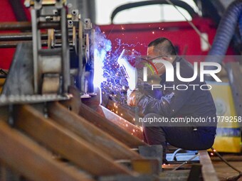 A worker works at a loader manufacturing enterprise in Qingzhou Economic Development Zone, East China's Shandong province, on November 15, 2...