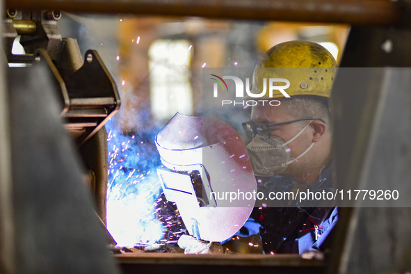 A worker works at a loader manufacturing enterprise in Qingzhou Economic Development Zone, East China's Shandong province, on November 15, 2...