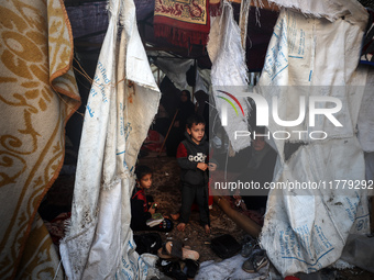 A child observes as Palestinians inspect the site of an Israeli strike on tents of displaced people in Deir Al-Balah, Gaza Strip, on Novembe...