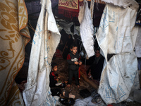 A child observes as Palestinians inspect the site of an Israeli strike on tents of displaced people in Deir Al-Balah, Gaza Strip, on Novembe...