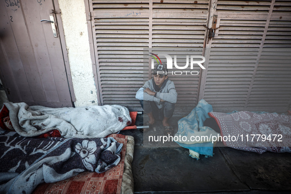 A Palestinian young man sits among the bodies of Palestinians killed in an Israeli airstrike on displaced persons' tents in Deir al-Balah, c...