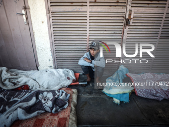 A Palestinian young man sits among the bodies of Palestinians killed in an Israeli airstrike on displaced persons' tents in Deir al-Balah, c...