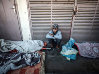 A Palestinian young man sits among the bodies of Palestinians killed in an Israeli airstrike on displaced persons' tents in Deir al-Balah, c...