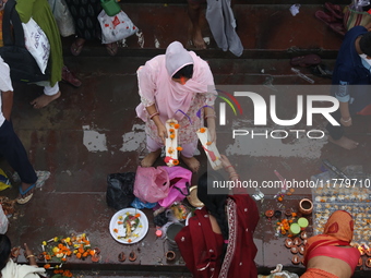 Hindu people offer prayers and float small decorated boats made with banana stems as people gather to take a holy dip in the river Ganges on...