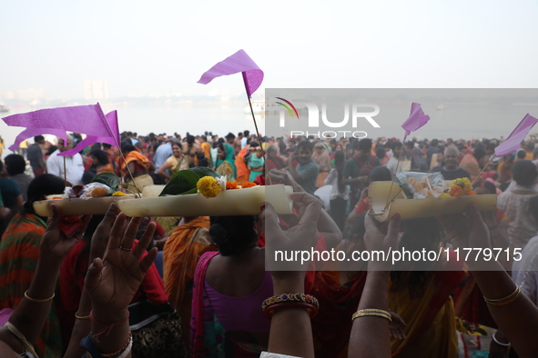 A Hindu man holds up a small decorated boat made with a banana stem as people gather to take a holy dip in the river Ganges on the occasion...