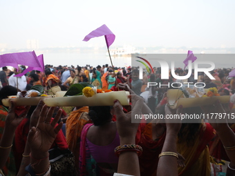 A Hindu man holds up a small decorated boat made with a banana stem as people gather to take a holy dip in the river Ganges on the occasion...