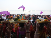 A Hindu man holds up a small decorated boat made with a banana stem as people gather to take a holy dip in the river Ganges on the occasion...