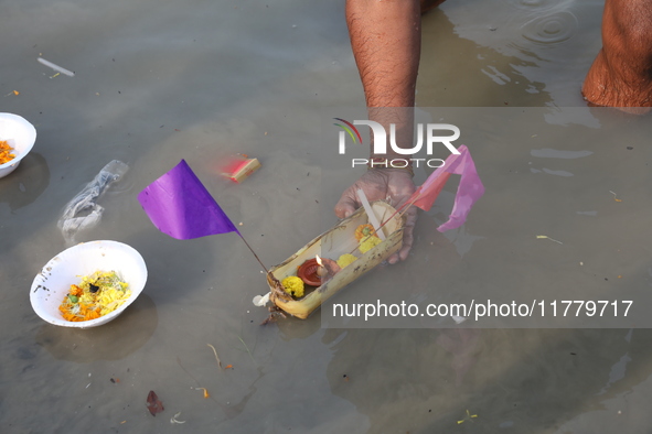 Hindu people float a small decorated boat made with a banana stem as people gather to take a holy dip in the river Ganges on the occasion of...