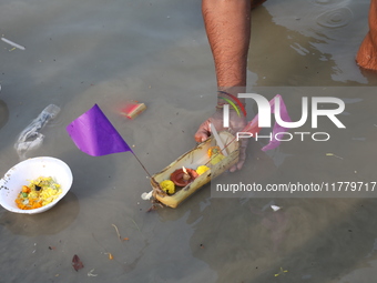 Hindu people float a small decorated boat made with a banana stem as people gather to take a holy dip in the river Ganges on the occasion of...