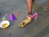 Hindu people float a small decorated boat made with a banana stem as people gather to take a holy dip in the river Ganges on the occasion of...