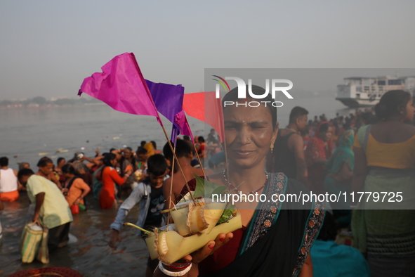 A Hindu man holds up a small decorated boat made with a banana stem as people gather to take a holy dip in the river Ganges on the occasion...