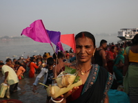 A Hindu man holds up a small decorated boat made with a banana stem as people gather to take a holy dip in the river Ganges on the occasion...