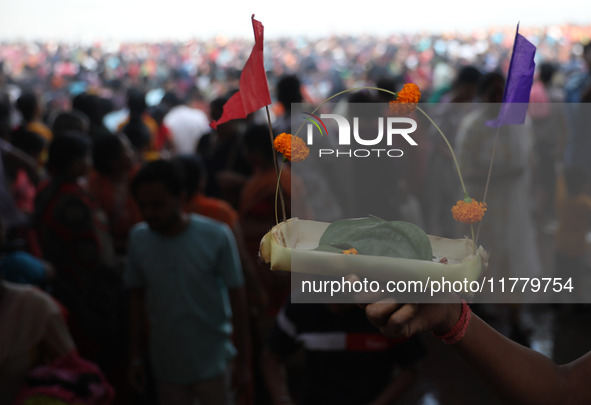 A Hindu man holds up a small decorated boat made with a banana stem as people gather to take a holy dip in the river Ganges on the occasion...