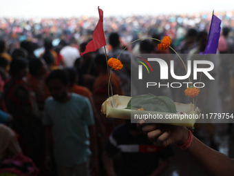 A Hindu man holds up a small decorated boat made with a banana stem as people gather to take a holy dip in the river Ganges on the occasion...