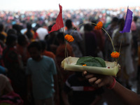 A Hindu man holds up a small decorated boat made with a banana stem as people gather to take a holy dip in the river Ganges on the occasion...