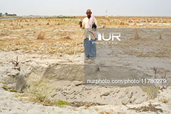 Shiv Shankar, a 66-year-old Indian buffalo herder, stands in front of a dry pit intended for water storage for agriculture as he returns wit...