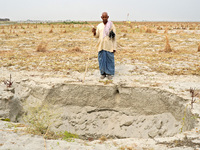 Shiv Shankar, a 66-year-old Indian buffalo herder, stands in front of a dry pit intended for water storage for agriculture as he returns wit...