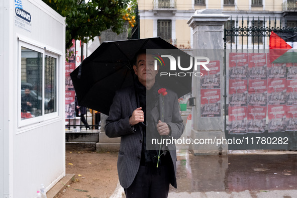 A man holds a carnation near a monument inside the Athens Polytechnic during the celebration of the 51st anniversary of the Polytechnic upri...