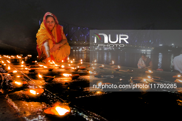 Hindu women devotees perform rituals at a ghat on the banks of the Hooghly River with the Howrah Bridge in the background on the occasion of...