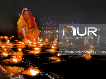 Hindu women devotees perform rituals at a ghat on the banks of the Hooghly River with the Howrah Bridge in the background on the occasion of...