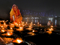 Hindu women devotees perform rituals at a ghat on the banks of the Hooghly River with the Howrah Bridge in the background on the occasion of...