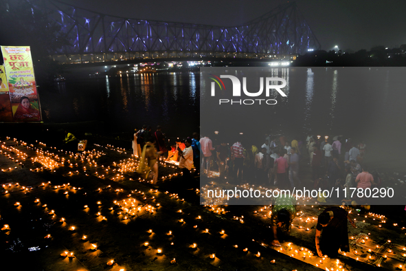 Hindu women devotees perform rituals at a ghat on the banks of the Hooghly River with the Howrah Bridge in the background on the occasion of...