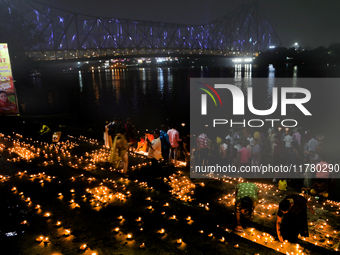 Hindu women devotees perform rituals at a ghat on the banks of the Hooghly River with the Howrah Bridge in the background on the occasion of...