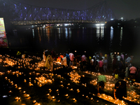 Hindu women devotees perform rituals at a ghat on the banks of the Hooghly River with the Howrah Bridge in the background on the occasion of...