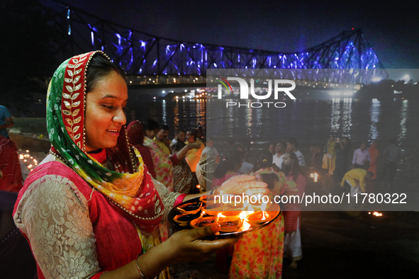 Hindu women devotees perform rituals at a ghat on the banks of the Hooghly River with the Howrah Bridge in the background on the occasion of...