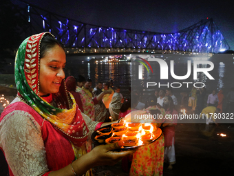 Hindu women devotees perform rituals at a ghat on the banks of the Hooghly River with the Howrah Bridge in the background on the occasion of...