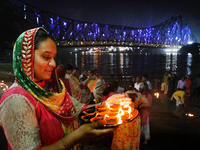 Hindu women devotees perform rituals at a ghat on the banks of the Hooghly River with the Howrah Bridge in the background on the occasion of...