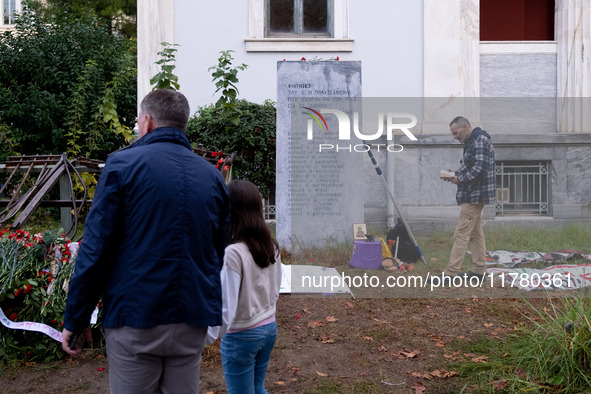 A man embraces his daughter while a man prays on a monument inside the Athens Polytechnic during the celebration of the 51st anniversary of...