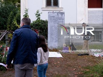 A man embraces his daughter while a man prays on a monument inside the Athens Polytechnic during the celebration of the 51st anniversary of...