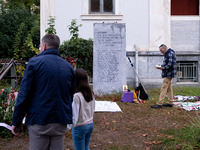 A man embraces his daughter while a man prays on a monument inside the Athens Polytechnic during the celebration of the 51st anniversary of...