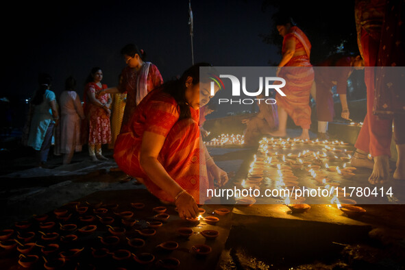 A lady lights oil lamps at the riverside of the Ganges in Kolkata, India, on November 15, 2024, during the Dev Deepavali celebration in the...