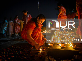 A lady lights oil lamps at the riverside of the Ganges in Kolkata, India, on November 15, 2024, during the Dev Deepavali celebration in the...