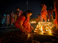 A lady lights oil lamps at the riverside of the Ganges in Kolkata, India, on November 15, 2024, during the Dev Deepavali celebration in the...