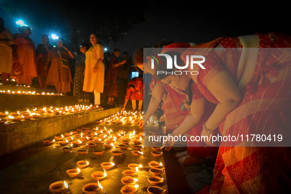 A lady lights oil lamps at the riverside of the Ganges in Kolkata, India, on November 15, 2024, during the Dev Deepavali celebration in the...