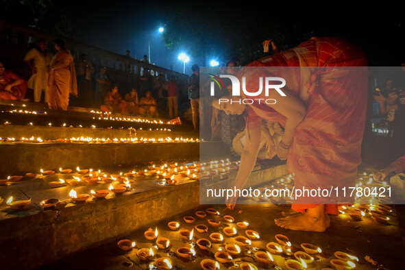 A lady lights oil lamps at the riverside of the Ganges in Kolkata, India, on November 15, 2024, during the Dev Deepavali celebration in the...