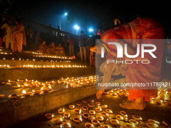 A lady lights oil lamps at the riverside of the Ganges in Kolkata, India, on November 15, 2024, during the Dev Deepavali celebration in the...