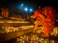 A lady lights oil lamps at the riverside of the Ganges in Kolkata, India, on November 15, 2024, during the Dev Deepavali celebration in the...