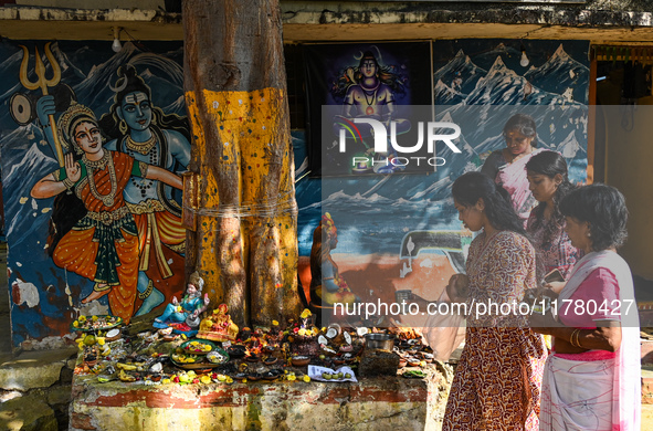 Hindu devotees perform rituals at the premises of a temple with murals of Hindu gods Lord Shiva and Parvathi on the occasion of Kartik Purni...