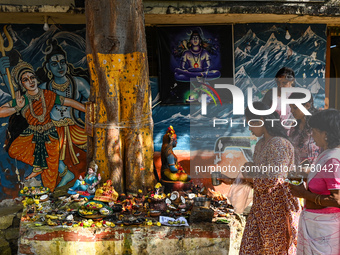 Hindu devotees perform rituals at the premises of a temple with murals of Hindu gods Lord Shiva and Parvathi on the occasion of Kartik Purni...