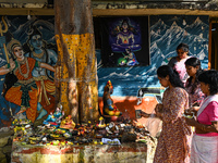 Hindu devotees perform rituals at the premises of a temple with murals of Hindu gods Lord Shiva and Parvathi on the occasion of Kartik Purni...