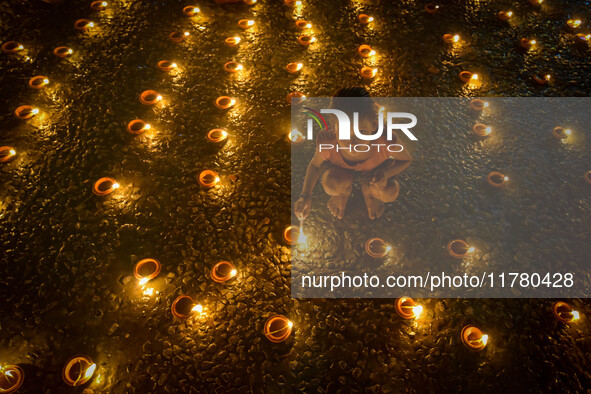 A child lights oil lamps at the riverside of the Ganges in Kolkata, India, on November 15, 2024, during the Dev Deepavali celebration in the...